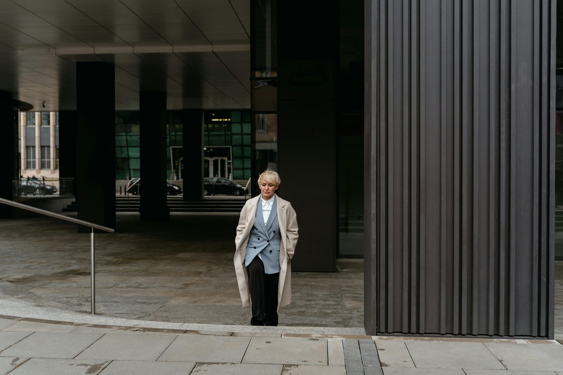 Person in a light coat walking in an urban area.